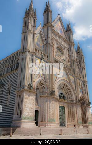 Orvieto, Region Umbrien, Italien. Die Außenansicht der Kathedrale von Orvieto aus dem Jahr 1330 hat eine farbenfrohe, gotische Fassade, die durch vier Säulen geteilt ist Stockfoto
