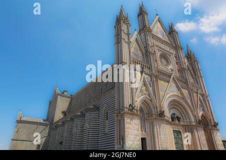 Orvieto, Region Umbrien, Italien. Die Außenansicht der Kathedrale von Orvieto aus dem Jahr 1330 hat eine farbenfrohe, gotische Fassade, die durch vier Säulen geteilt ist Stockfoto