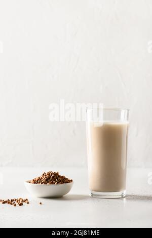 Buchweizenmilch in Trinkglas mit Getreidebestandteil auf weißem Hintergrund serviert. Konzept gesunder laktosefreier und pflanzenbasierter veganer Milchaustauscher. Stockfoto