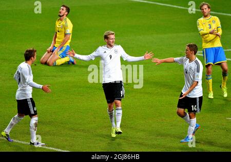 Andre Schuerrle (C) feiert das Tor mit den Teamkollegen Mario Goetze (L) und Max Kruse, während die Schweden per Nilsson (Far L) und Mikael Antonsson beim Qualifying-Fußballspiel der Gruppe C 2014 zwischen Schweden und Deutschland in der Friends Arena in Stockholm, Schweden, am 15. Oktober 2013 niedergeschlagen wirken. Poto: Jonas Ekstromer / TT / Code 10030 Stockfoto