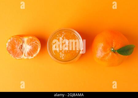 Mandarinmarmelade und Zutaten auf orangefarbenem Hintergrund Stockfoto