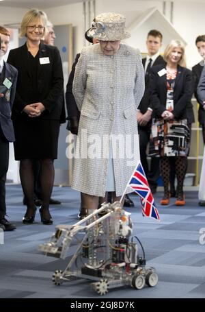 Die britische Königin Elizabeth II. Sieht sich eine Roboterdemonstration an, als sie am Donnerstag, März, in Cobham, England, die Reed's School besucht. 6, 2014. Die Schule wurde ursprünglich 1813 im östlichen Teil Londons als Londoner "The London"-Asyl gegründet. Die Königin, die die Patronin der Schule ist, besucht sie, um ihr zu helfen, das 200. Jubiläum zu feiern. (AP Photo/Alastair Grant, Pool) Stockfoto