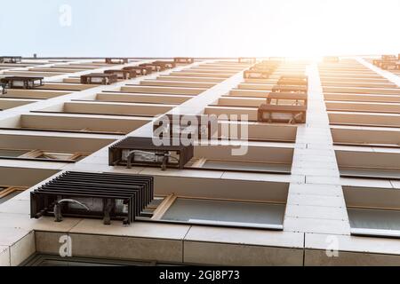 Unten pov der neuen modernen Wohn-Wohnung Bürogebäude Fassade mit vielen Klimaanlagen montiert durch Metallgehäuse gegen Himmel und Sonne bedeckt Stockfoto
