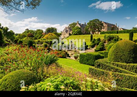 Die farbenfrohen Grenzen und das Topiary im italienischen Fountain Court Garten im Mapperton House, Dorset, England, Großbritannien Stockfoto