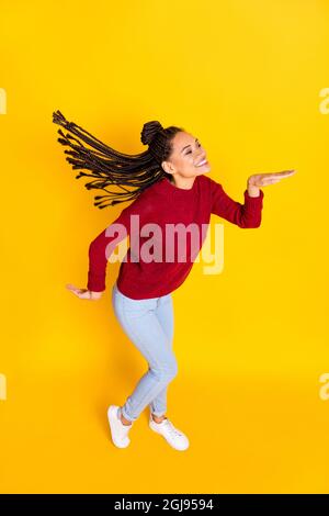 Vertikale voller Länge Foto von süßen lustigen dunklen Haut Dame tragen roten Pullover lächelnd tanzen isoliert gelben Hintergrund Stockfoto