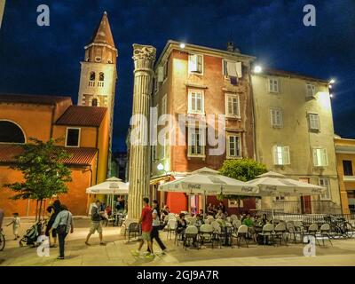 Kroatien. Dalmatien. Zadar. 16. September 2013. Nachtansicht eines Straßencafés und einer antiken römischen Säule auf dem Stadtplatz von Zadar. (Redaktionelle Verwendung Stockfoto