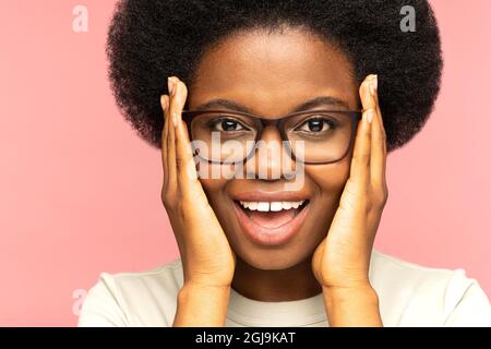Überglücklich afrikanisch weiblich emotional mit offenem Mund. Aufgeregt junge schwarze Frau in Brillen erstaunt Stockfoto