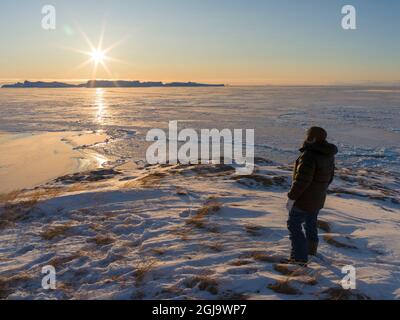 Besucher, der den Sonnenuntergang genießt. Winter am Ilulissat Fjord, der in der Disko Bay in Westgrönland liegt, ist der Fjord Teil des UNESCO-Weltkulturerbes S Stockfoto