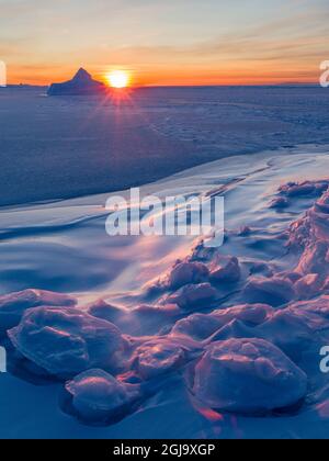 Sonnenuntergang am Ufer der gefrorenen Disko Bay im Winter, Westgrönland, Dänemark Stockfoto