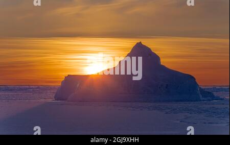 Sonnenuntergang am Ufer der gefrorenen Disko Bay im Winter, Westgrönland, Dänemark Stockfoto