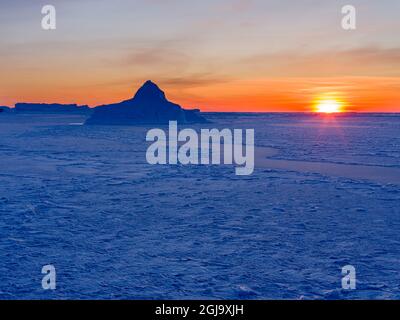 Sonnenuntergang am Ufer der gefrorenen Disko Bay im Winter, Westgrönland, Dänemark Stockfoto