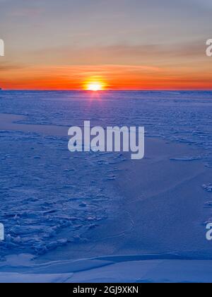 Sonnenuntergang am Ufer der gefrorenen Disko Bay im Winter, Westgrönland, Dänemark Stockfoto