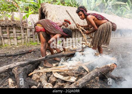 Wamena, Indonesien - 9. Januar 2010: Dani-Frauen kochen in einem Loch mit heißen Steinen. Stockfoto