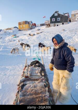 Zurück von der Jagd. Der Jäger trägt traditionelle Hosen und Stiefel aus Eisbärenpelz. Das traditionelle und abgelegene grönländische Inuit-Dorf Stockfoto