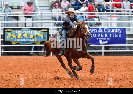 Frau, die mit ihrem Pferd bei einem Rodeo an einem Barrel-Rennen teilnahm Stockfoto