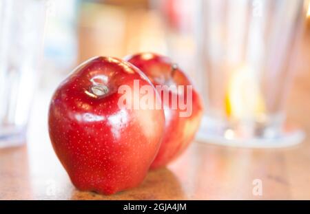 Gesunde rote Äpfel auf einem Tisch mit Wassergläsern im Hintergrund. Stockfoto