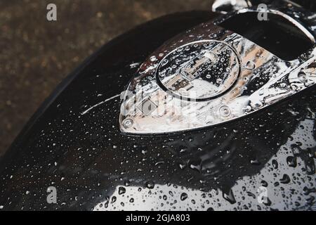 Fahrrad mit Wassertropfen bedeckt nach Regen. Schwarzer Benzintank mit Metalldeckel. Fahrzeuglagerung im Freien. Nahaufnahme. Stockfoto