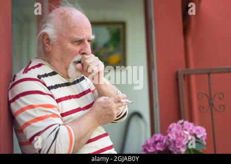 Rentner alter Mann, der raucht und hustet. Ein ungesundes Leben. Stockfoto