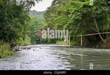 Luwu, Indonesien. September 2021. Zwei Bewohner überqueren einen Fluss mit einer schwer beschädigten Brücke in Malela.Obwohl es gefährlich ist, wird die von der Flut beschädigte Brücke jeden Tag von den Bewohnern genutzt, um die Fahrzeit zu anderen Dörfern zu reduzieren. (Foto: Hariandi Hafid/SOPA Images/Sipa USA) Quelle: SIPA USA/Alamy Live News Stockfoto