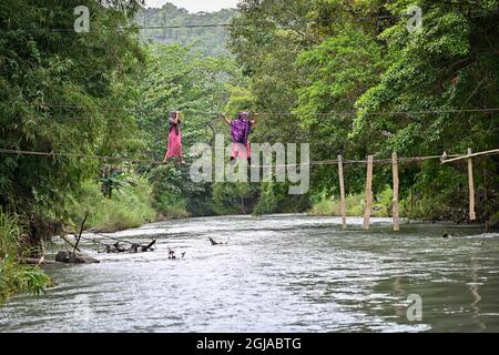 Luwu, Indonesien. September 2021. Zwei Bewohner überqueren einen Fluss mit einer schwer beschädigten Brücke in Malela.Obwohl es gefährlich ist, wird die von der Flut beschädigte Brücke jeden Tag von den Bewohnern genutzt, um die Fahrzeit zu anderen Dörfern zu reduzieren. (Foto: Hariandi Hafid/SOPA Images/Sipa USA) Quelle: SIPA USA/Alamy Live News Stockfoto