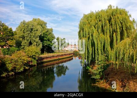 Ein Blick auf den Fluss Wensum mit Reflexionen stromaufwärts der Fußgängerbrücke St. Helen's Wharf in der Stadt Norwich, Norfolk, England, Vereinigtes Königreich. Stockfoto