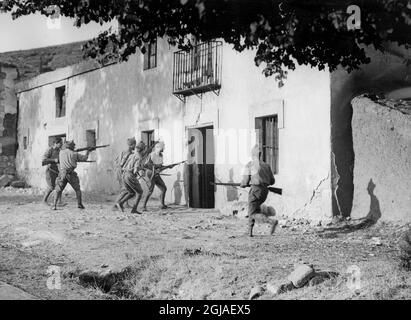 Nach dem Fall von Irun, der immer noch brennt, durften die Rebellen einreisen, als die Flammen ein wenig verglühen waren, und sich in einer kleinen Runde auf eine aufwischende Expedition begeben. Es gibt immer noch eine beträchtliche Menge an Scharfschützen von Rotweinen, die in Bauernhäusern usw. verwurzelt sind, um die Rebellen auf ihrem Vormarsch zu stoppen. O.K. Rebellische Soldaten greifen ein Farmhaus an, von dem sie glauben, dass es mehrere rote Scharfschützen gibt. Stockfoto