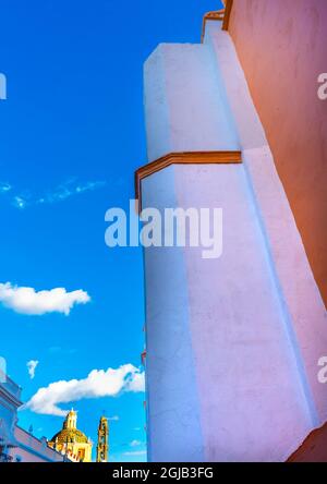 Orangefarbene Fassade Kirche Santa Clara de Asis, Puebla, Mexiko. Sam Cristobal Kirche im Hintergrund. Stockfoto