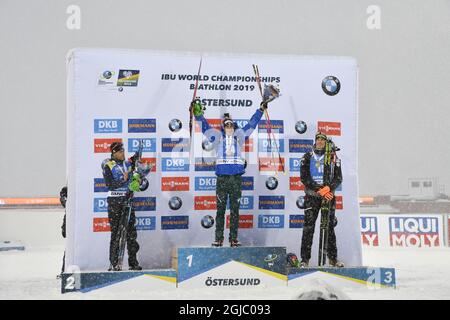 (L-R) Zweiter platzierter Julian Eberhard aus der Schweiz, Sieger Dominik Windisch aus Italien und dritter platzierter Antonin Guigonnat aus Frankreich feiern am 17. März 2019 auf dem Podium nach dem 15-km-Massenstartwettbewerb der Männer bei den IBU-Biathlon-Weltmeisterschaften im schwedischen Oestersund. Foto: Jessica Gow / TT / Code 10070 Stockfoto