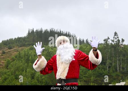 Junger Mann in einem Weihnachtsmann-Anzug, der eine lustige Pose im Freien macht Stockfoto