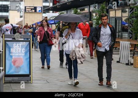 Bristol, Großbritannien. August 2021. Eine Frau wird bei Regen neben einem Schutzdach eines Mannes unter einem Regenschirm laufen gesehen. (Foto: Dinendra Haria/SOPA Images/Sipa USA) Quelle: SIPA USA/Alamy Live News Stockfoto