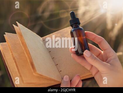 Kräuterextrakt in einer Pipette - Platz für Text kopieren. Eine Frau, die eine medizinische Flasche und ein leeres Notizbuch in der Hand hält. Alternative Medizin - NACHBAU. Stockfoto