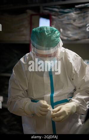 Bologna, ITALIEN. 10. März 2021. Ein Mitarbeiter des Gesundheitswesens kleidet sich, um in die Intensivstation der „Ospedale MaggioreÓ zu gelangen. Bologna ist eine der am stärksten betroffenen Städte b Stockfoto