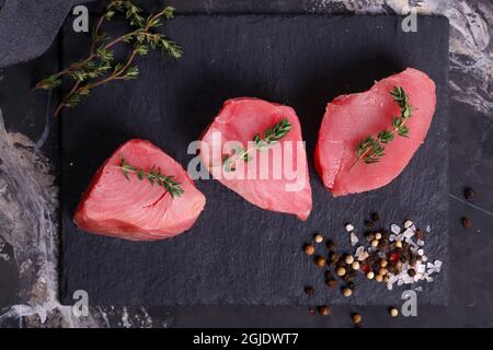 Rohe, frische Thunfisch-Steaks auf schwarzem Hintergrund Stockfoto