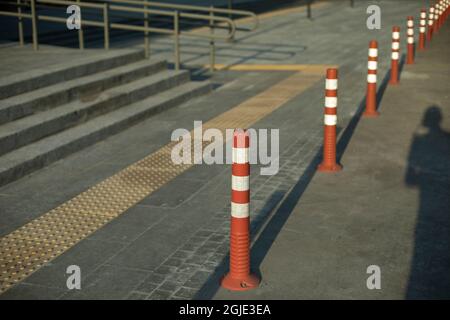 Parkposten in der Stadt. Schilder, die die Bewegung von Fahrzeugen einschränken. Orangefarbene weiße Warnhinweise halten an. Stockfoto