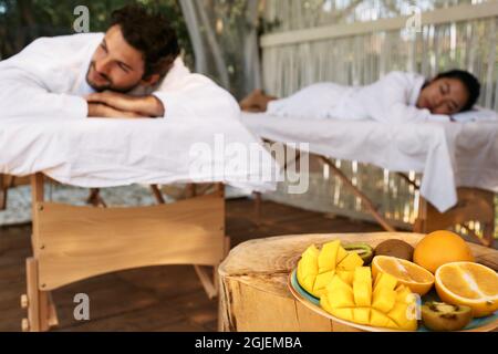 Paare liegen auf Massagetischen während eines Tages-Spa und ein romantisches Wochenende mit exotischen Früchten im Spa Resort. Massage für Paare Stockfoto