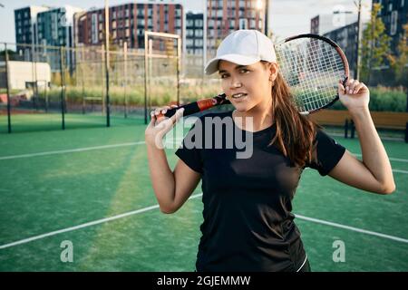 Portrait einer schönen Tennisspielerin mit Tennisschläger auf dem städtischen Tennisplatz im Sommer an einem sonnigen Tag Stockfoto