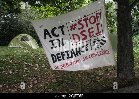 London, Großbritannien. September 2021. Banner für das Stop-DSEI-Camp am Eingang zum Excel-Zentrum, wo über 30 Zelte Aktivisten beherbergen, die 10 Tage lang gegen die DSEI-Waffenmesse im Osten Londons protestieren, eine der größten Waffenmessen der Welt, die nächste Woche eröffnet wird. Peter Marshall/Alamy Live News Stockfoto