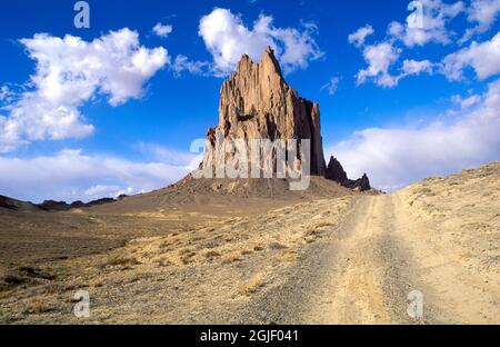 Nachmittags-Licht auf Shiprock und Schotterstraße, Navajo Indianerreservat, New Mexico, USA. Stockfoto