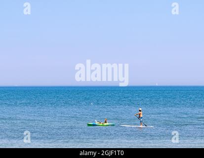 Pärchen paddeln beim Boarding und Kajakfahren am Gin Beach in Montauk, NY Stockfoto