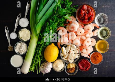 Shrimps and Crab Bisque Zutaten auf einem Holztisch: Gefrorene Garnelen und blaues Krabbenfleisch mit anderen rohen Zutaten auf einem Holzhintergrund Stockfoto