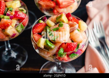 Erdbeer-Garnelen-Ceviche-Cocktails in Coupé-Gläsern: Garnelensalat in einer Champagneruntertasse im Cocktailstil Stockfoto