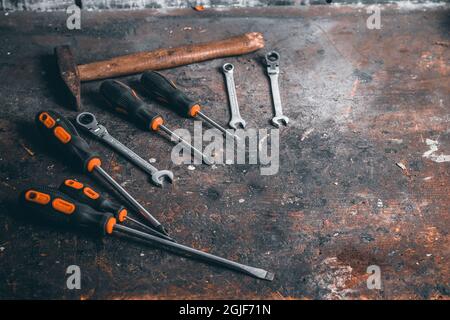 Schraubendreher, Schraubenschlüssel und Hammer auf eine hölzerne Werkbank. Draufsicht auf Arbeitswerkzeuge mit Platz für Text. Bauwerkzeuge auf Arbeitstisch aus Holz. Stockfoto