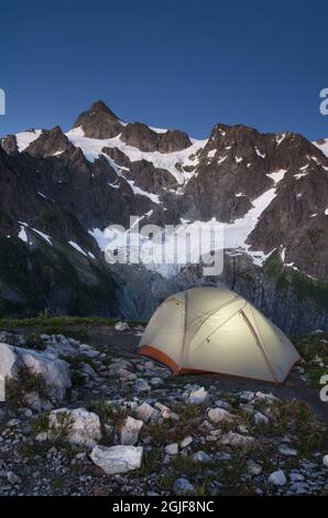 USA, Staat Washington. Zelt beleuchtet im Backcountry Camp auf dem Bergrücken über Lake Ann, Mount Shuksan im Hintergrund, Mount Baker Wilderness North Cas Stockfoto