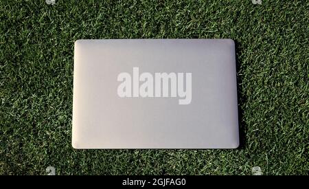 Laptop auf grünem Gras. Agiles Business. Fernlernkonzept. Immer online verfügbar Stockfoto