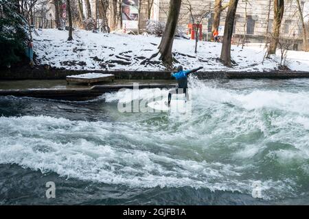 Surfer fahren stromaufwärts im Eisbach in München. Stockfoto