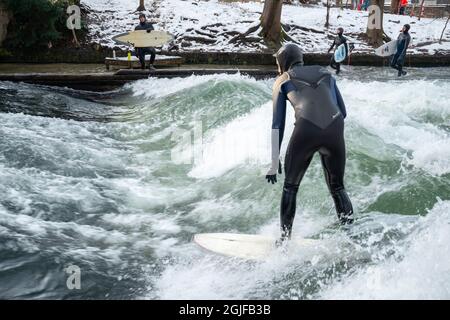 Surfer fahren stromaufwärts im Eisbach in München. Stockfoto