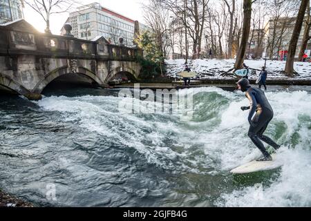 Surfer fahren stromaufwärts im Eisbach in München. Stockfoto