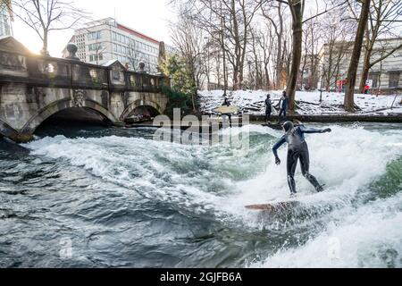 Surfer fahren stromaufwärts im Eisbach in München. Stockfoto