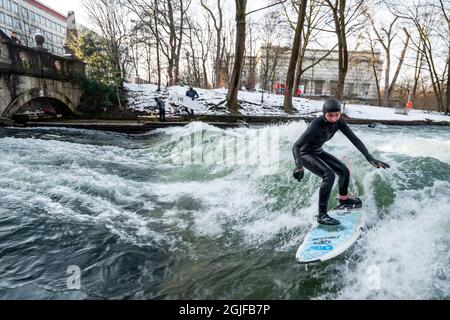 Surfer fahren stromaufwärts im Eisbach in München. Stockfoto