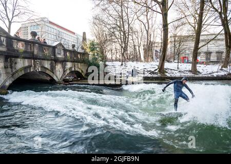 Surfer fahren stromaufwärts im Eisbach in München. Stockfoto